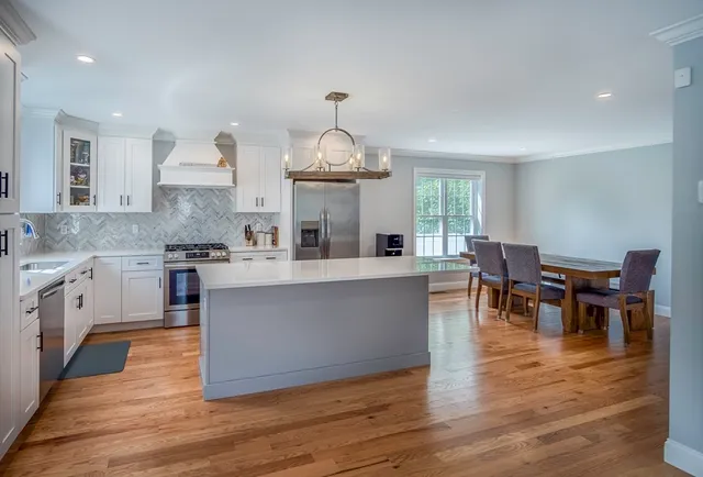 a large white kitchen with lots of counter space and breakfast area