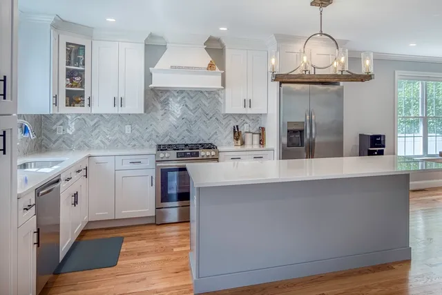 a kitchen with stainless steel appliances granite countertop a stove a sink and a wooden floors
