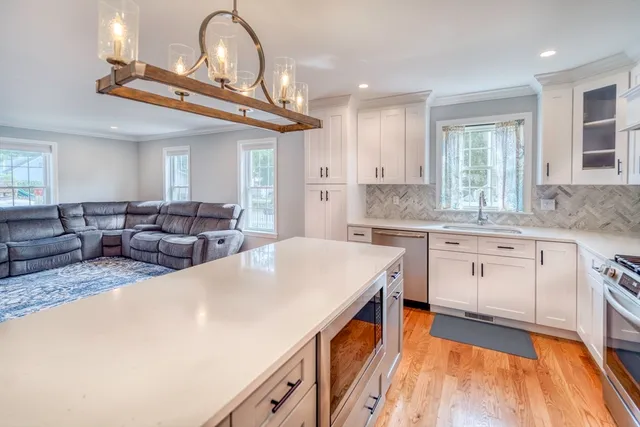 a large white kitchen with a large window a sink and stainless steel appliances