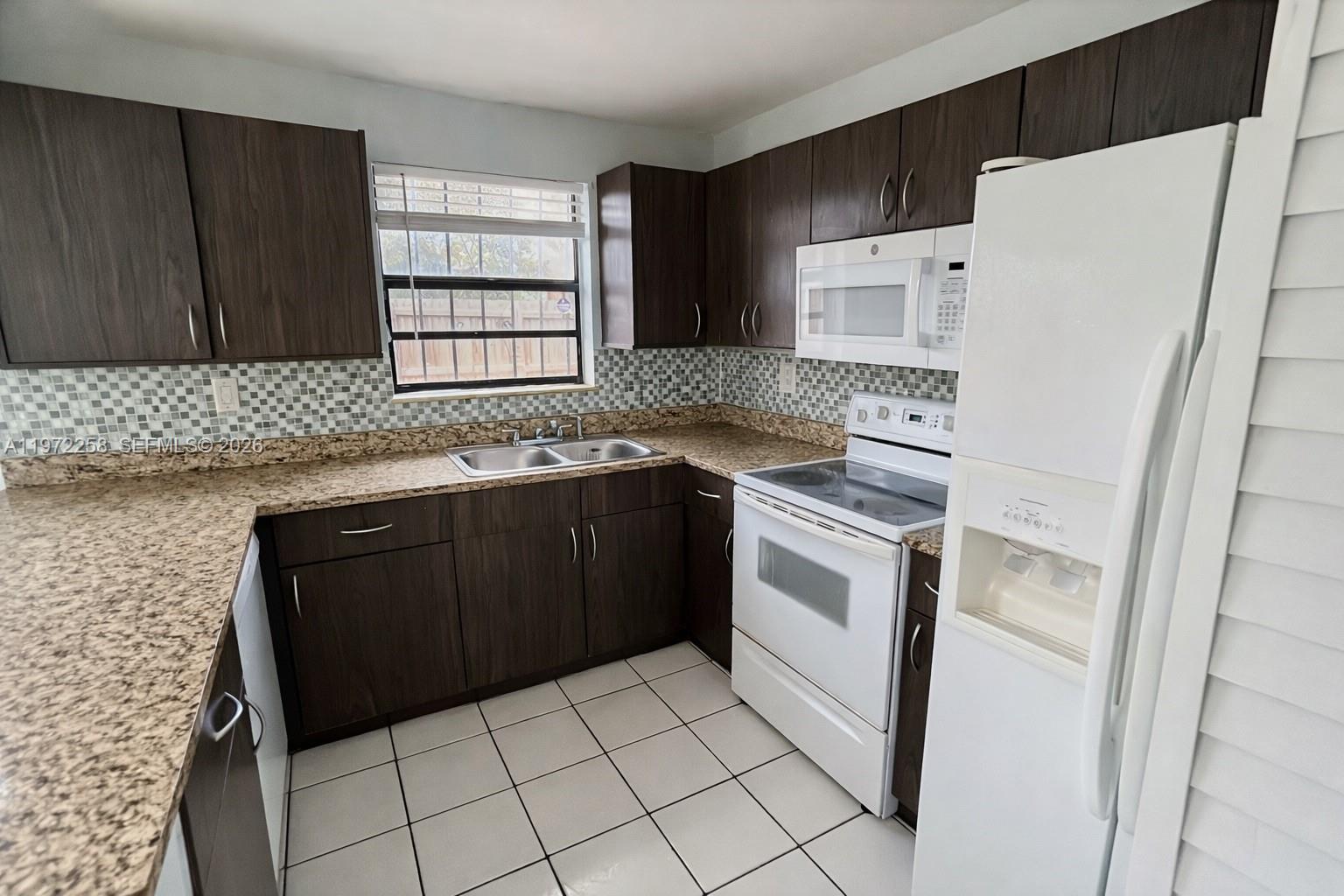 10900 Northwest 7th Street, Unit 101 Miami, FL 33172 - Photo 2 of 10 a kitchen with a sink a stove a refrigerator and cabinets