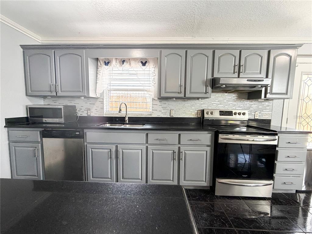 141 South Hiawassee Road Orlando, FL 32835 - Photo 6 of 30 a kitchen with stainless steel appliances granite countertop a stove a sink and a microwave
