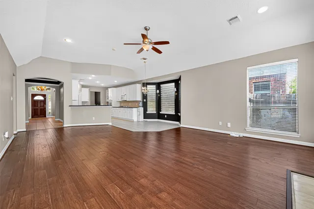 a view of an empty room with wooden floor and a window