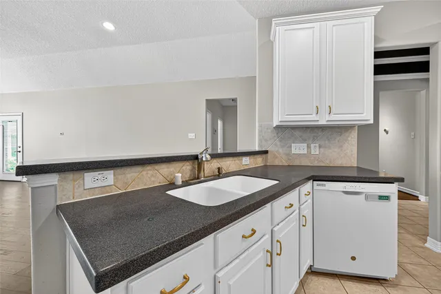 a kitchen with granite countertop a sink dishwasher white cabinets and a granite counter tops