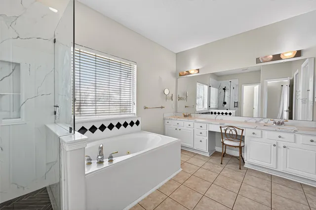 a large white bathroom with a sink a bathtub and a double vanity sink