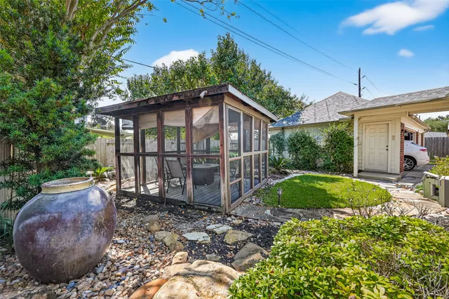 a view of a backyard with plants and large trees