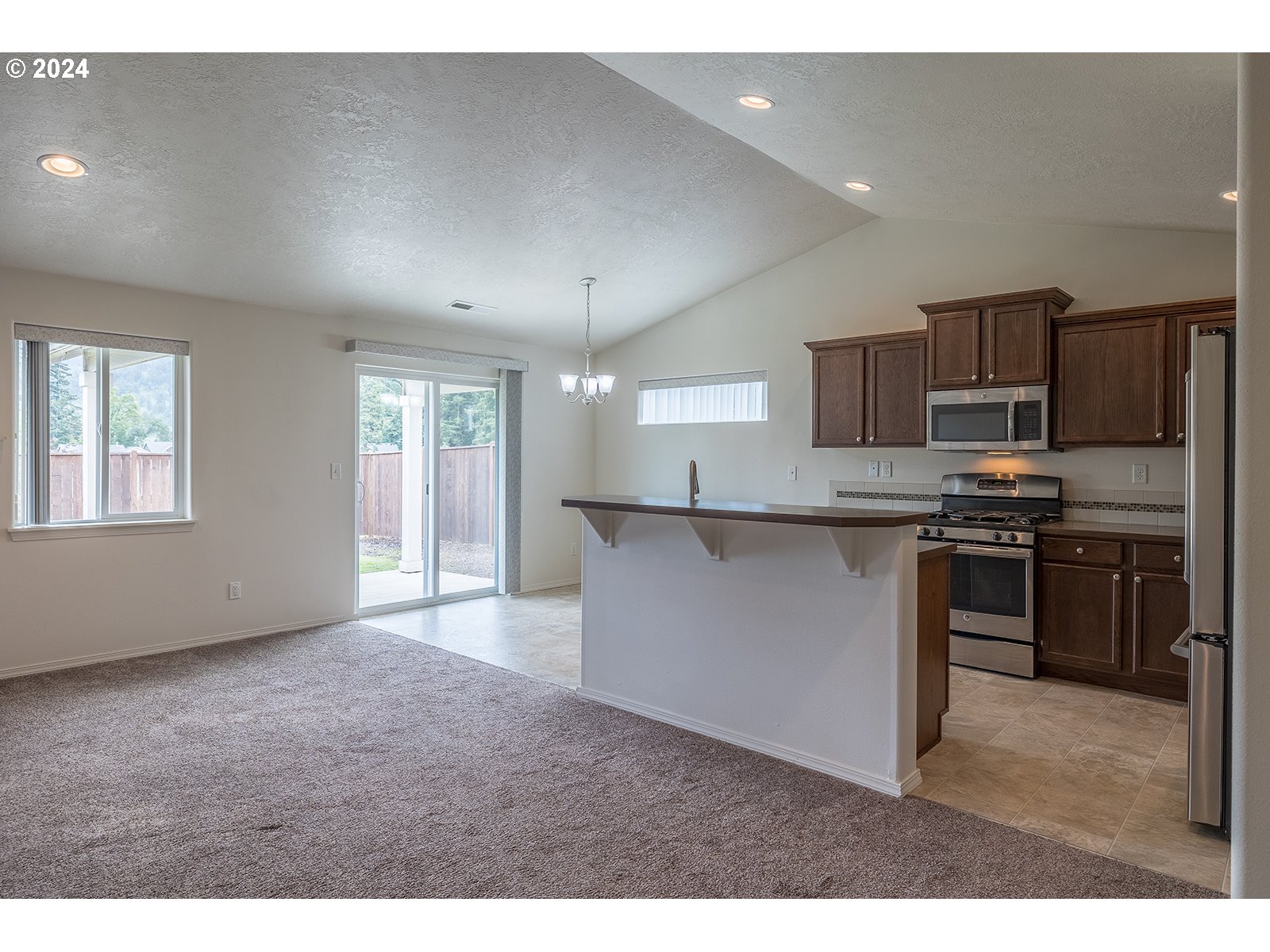 941 South 55th Street Springfield, OR 97478 - Photo 5 of 24 a kitchen with kitchen island granite countertop a sink cabinets and stainless steel appliances