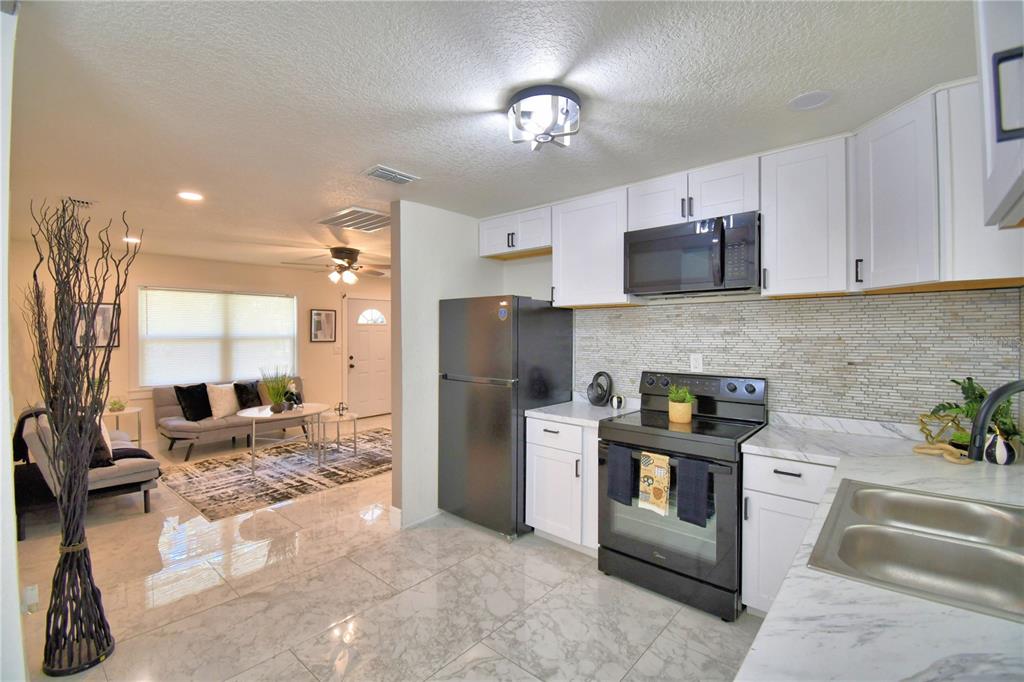 6960 2nd Street Mulberry, FL 33860 - Photo 16 of 39 a kitchen with stainless steel appliances granite countertop a stove refrigerator and a sink