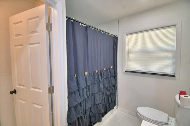 a bathroom with a toilet a sink and shower curtain