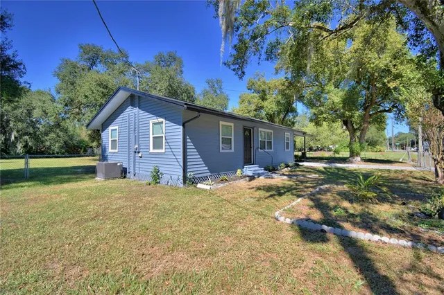 a view of a house with backyard and trees