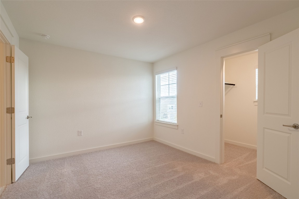 7400 Sparkling Light Drive, Unit A Del Valle, TX 78617 - Photo 13 of 22 Unfurnished bedroom with light carpet and a walk in closet