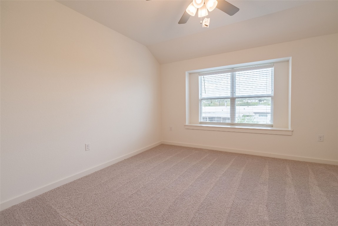 7400 Sparkling Light Drive, Unit A Del Valle, TX 78617 - Photo 16 of 22 Empty room with carpet, lofted ceiling, and ceiling fan