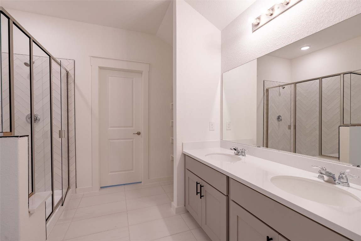 7400 Sparkling Light Drive, Unit A Del Valle, TX 78617 - Photo 18 of 22 Full bathroom with double vanity, light tile patterned flooring, and a shower stall