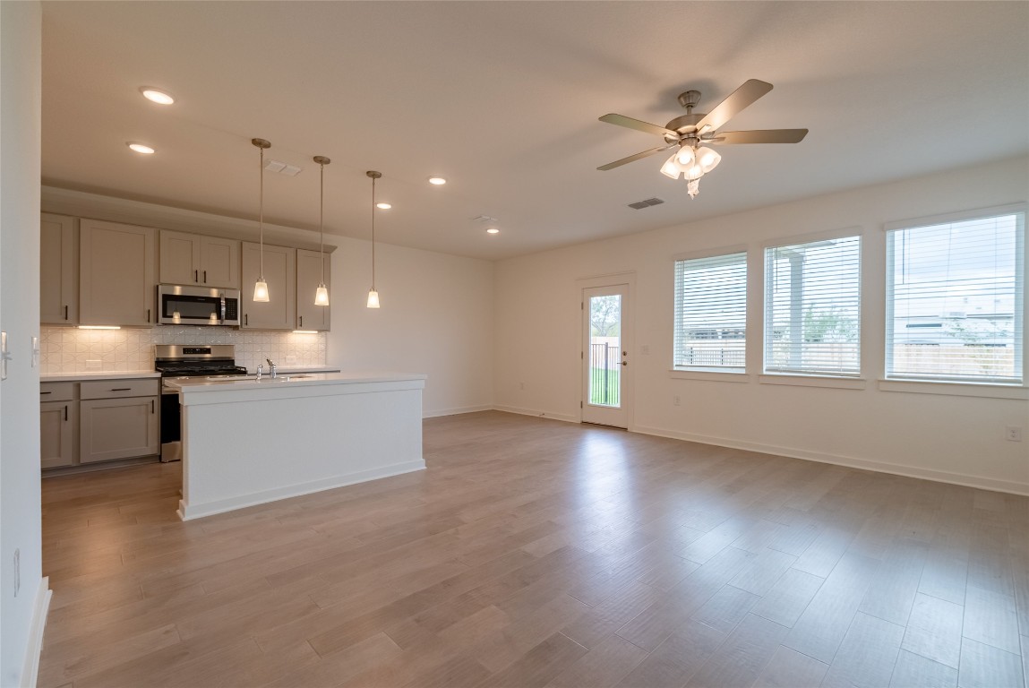 7400 Sparkling Light Drive, Unit A Del Valle, TX 78617 - Photo 22 of 22 Kitchen featuring a center island with sink, pendant lighting, tasteful backsplash, appliances with stainless steel finishes, and open floor plan