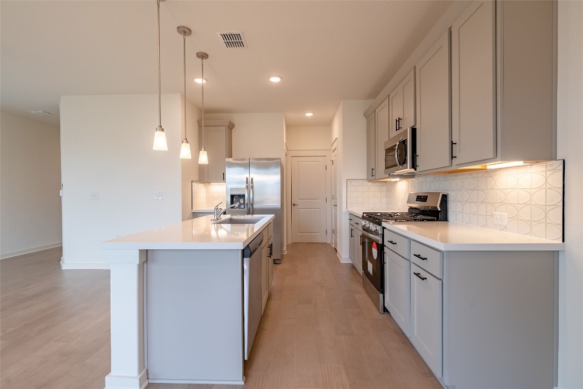 7400 Sparkling Light Drive, Unit A Del Valle, TX 78617 - Photo 5 of 22 Kitchen featuring stainless steel appliances, backsplash, decorative light fixtures, a center island with sink, and recessed lighting
