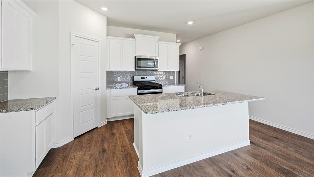 403 Flintlock Road Caddo Mills, TX 75135 - Photo 24 of 26 Kitchen featuring stainless steel appliances, light stone countertops, decorative backsplash, a center island with sink, and recessed lighting