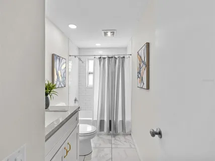 a bathroom with a granite countertop sink a toilet and shower