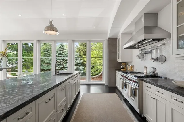 a kitchen with stainless steel appliances granite countertop a sink a stove and a wooden floors