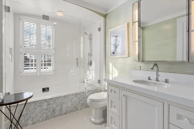 a bathroom with a granite countertop sink toilet a large mirror a shower and a bathtub