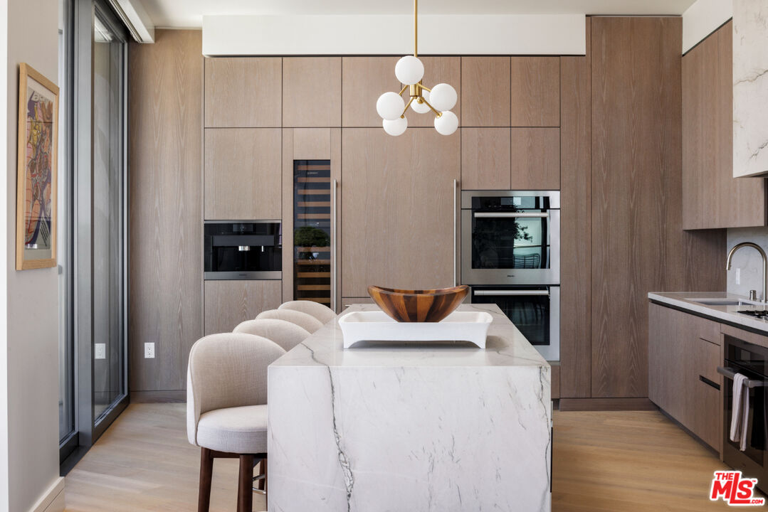 211 Elm Court, Unit 39B Los Angeles, CA 90067 - Photo 3 of 29 a kitchen with stainless steel appliances kitchen island granite countertop a table chairs in it and wooden floors