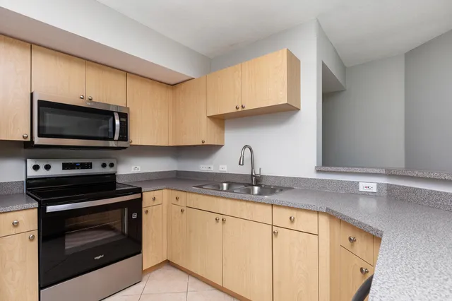 a kitchen with granite countertop a sink dishwasher stove and microwave with wooden cabinets
