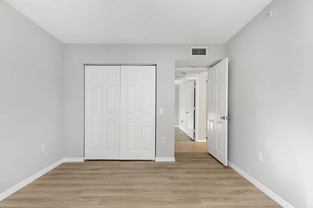 a view of a hallway with wooden floor and closet area