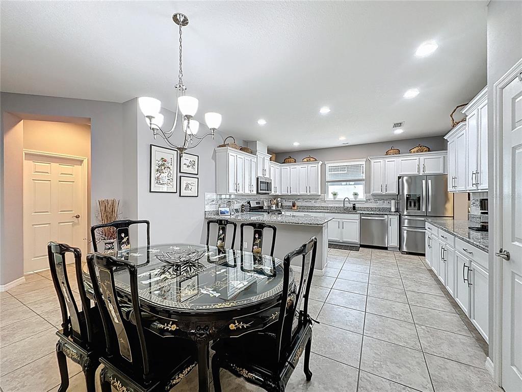 277 Silver Maple Road Groveland, FL 34736 - Photo 12 of 81 a kitchen with stainless steel appliances kitchen island granite countertop a dining table chairs and a refrigerator