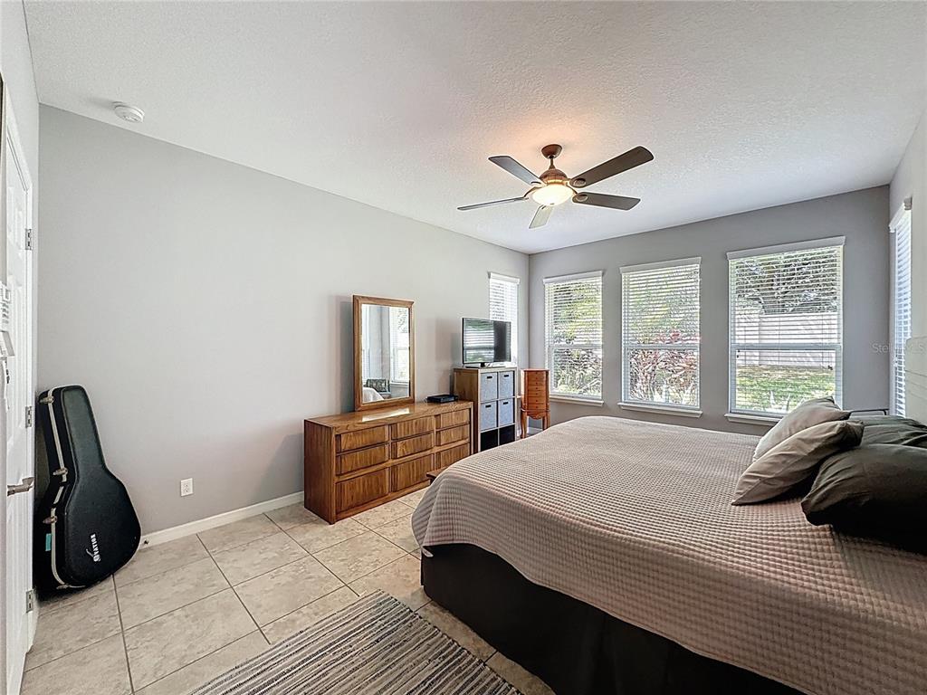 277 Silver Maple Road Groveland, FL 34736 - Photo 29 of 81 a bedroom with a bed a window and a chandelier