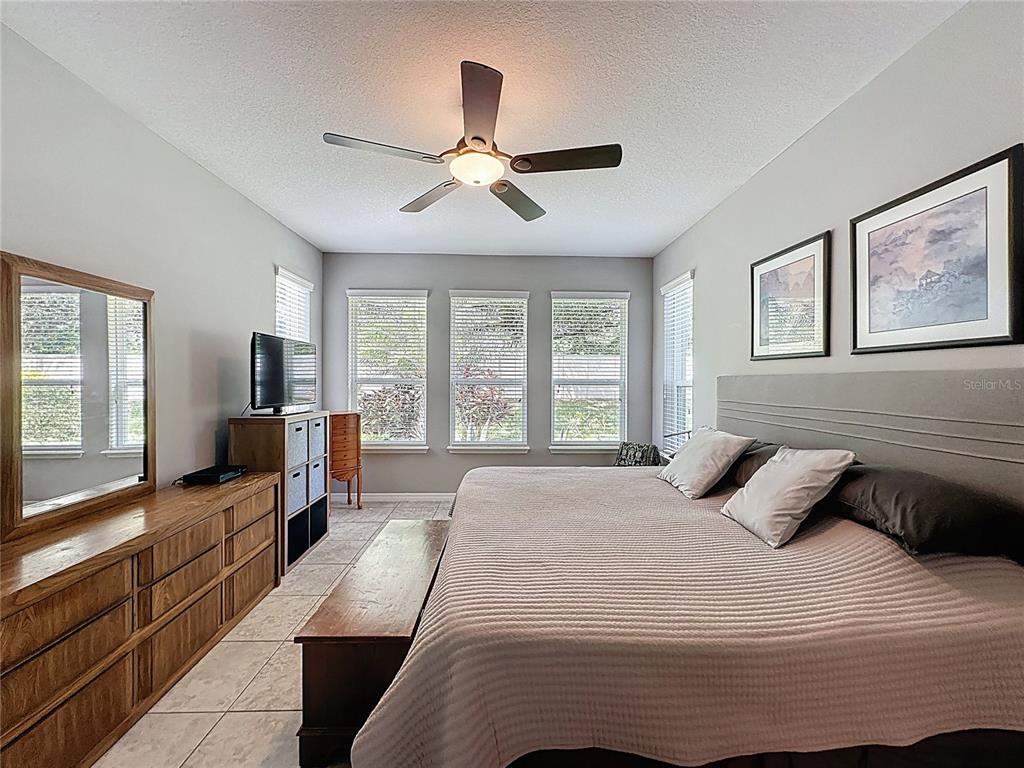 277 Silver Maple Road Groveland, FL 34736 - Photo 30 of 81 a bedroom with a large bed and a flat tv screen on dresser