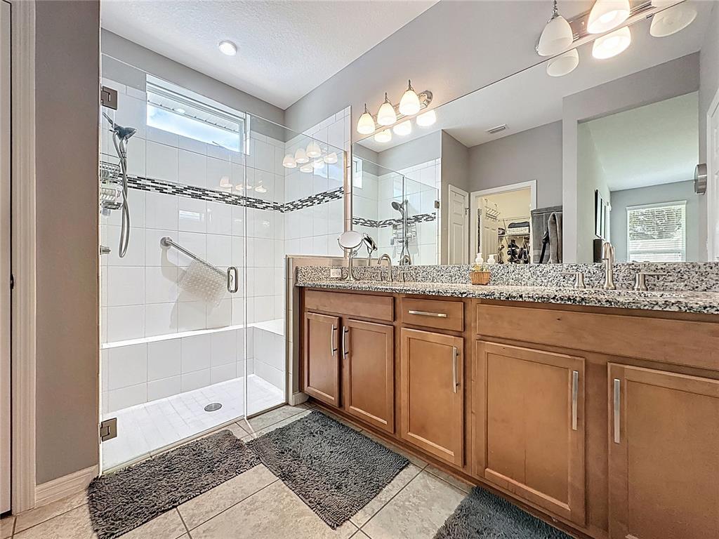 277 Silver Maple Road Groveland, FL 34736 - Photo 34 of 81 a bathroom with a granite countertop sink a mirror and a shower