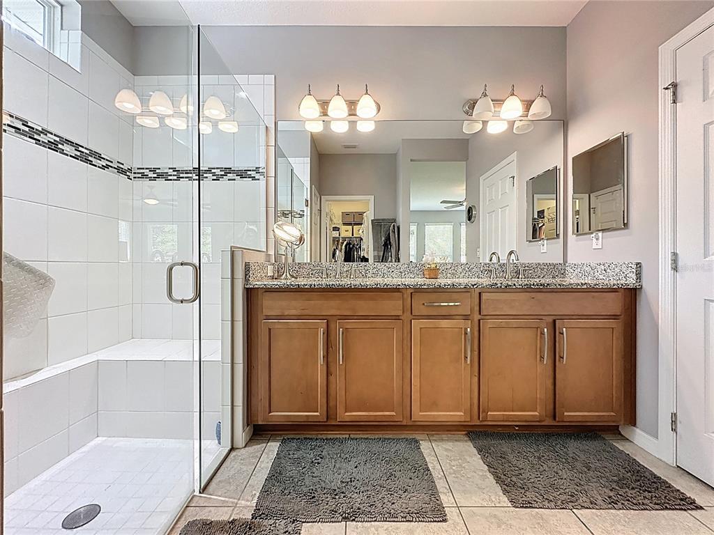 277 Silver Maple Road Groveland, FL 34736 - Photo 35 of 81 a bathroom with a granite countertop sink a mirror and a shower
