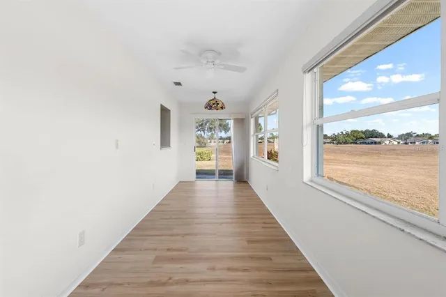 a view of a hallway with wooden floor and windows
