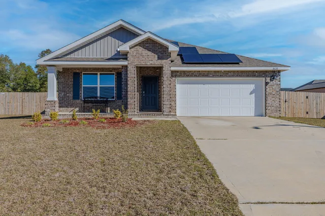 a front view of a house with yard and trees in the background