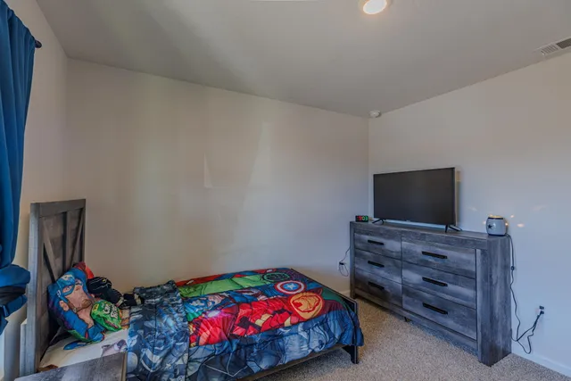 a bedroom with a bed and a flat tv screen on dresser