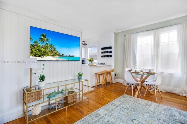 a view of a dining room with furniture one side kitchen view and wooden floor