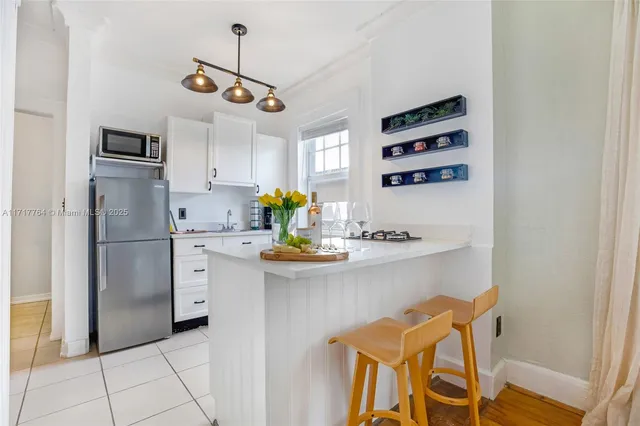 a kitchen with stainless steel appliances a stove a refrigerator and white cabinets with wooden floor