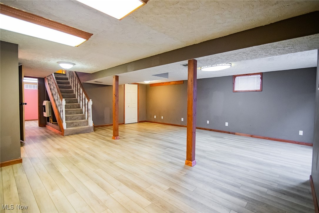 91 Mike Street Washington, WV 26181 - Photo 26 of 42 Basement with stairs, a textured ceiling, and light wood-style flooring