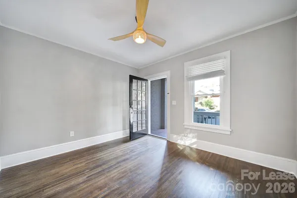 a view of an empty room with wooden floor and a window