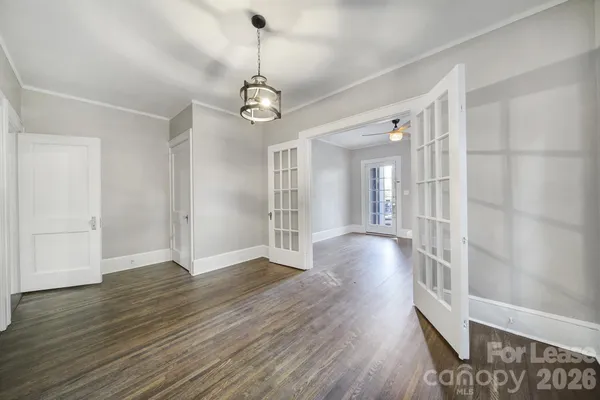 a view of an empty room with wooden floor and windows