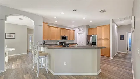 a kitchen with stainless steel appliances granite countertop a refrigerator a stove a sink a washer dryer and chairs