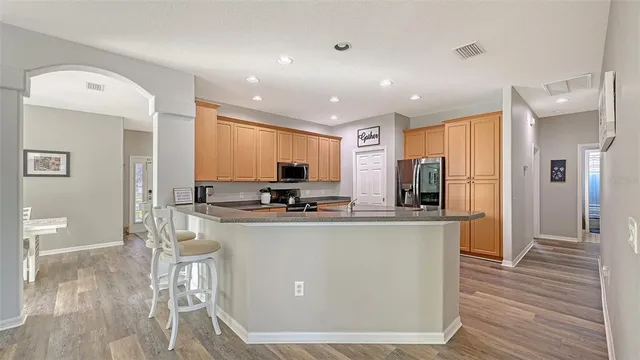 a kitchen with stainless steel appliances granite countertop a refrigerator a stove a sink a washer dryer and chairs