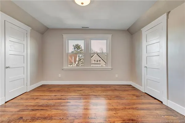 an empty room with wooden floor and window