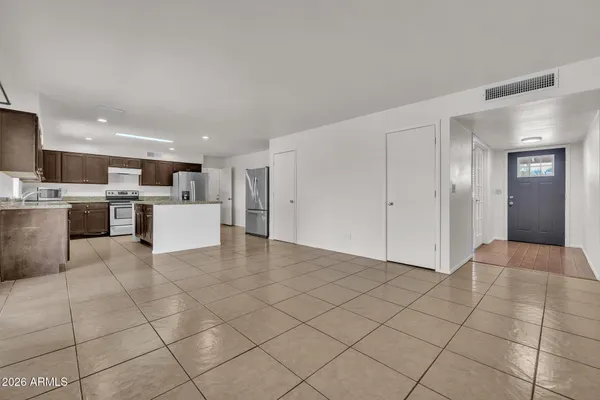 a view of a electric appliances in kitchen and empty room with wooden floor