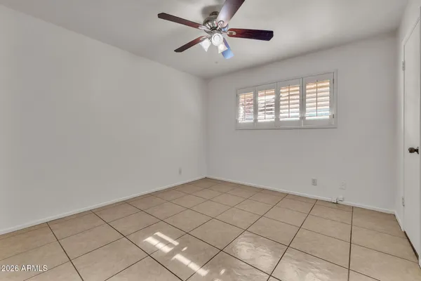 an empty room with windows and chandelier fan