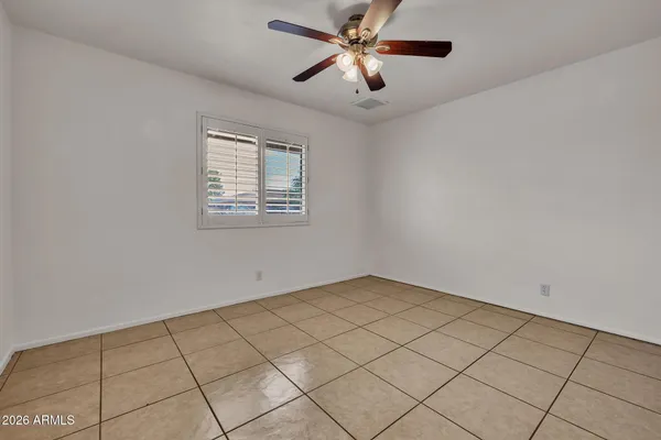 an empty room with a ceiling fan and carpet