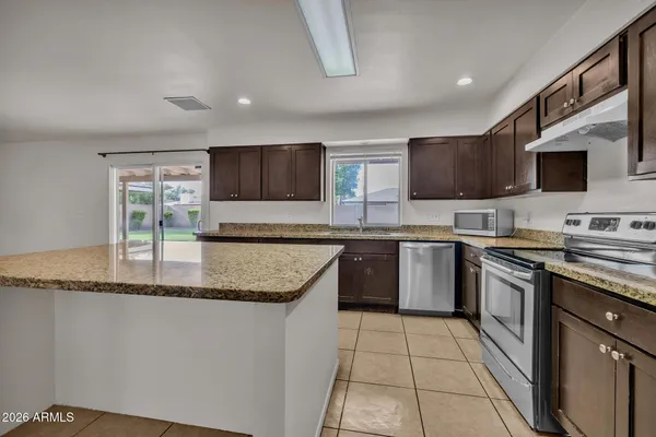 a kitchen with stainless steel appliances granite countertop a stove top oven a sink dishwasher and a refrigerator
