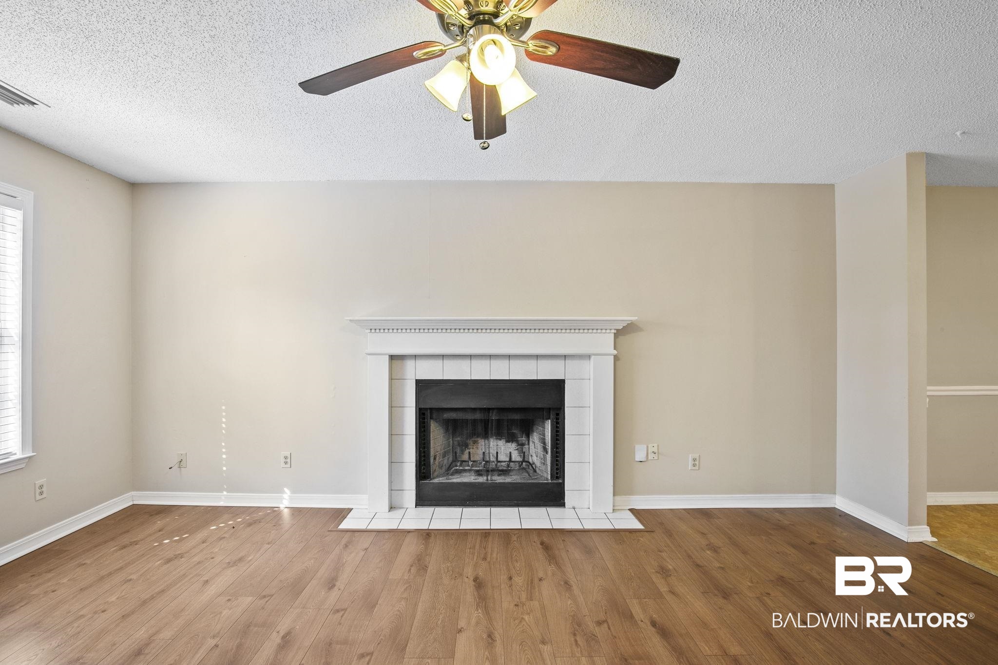 359 Ridgewood Drive Daphne, AL 36526 - Photo 14 of 73 Living room with wood burning fireplace, LVP flooring and ceiling fan.