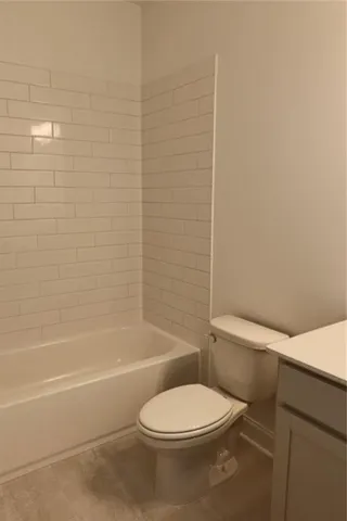 a white toilet and tub sitting next to a bathroom sink