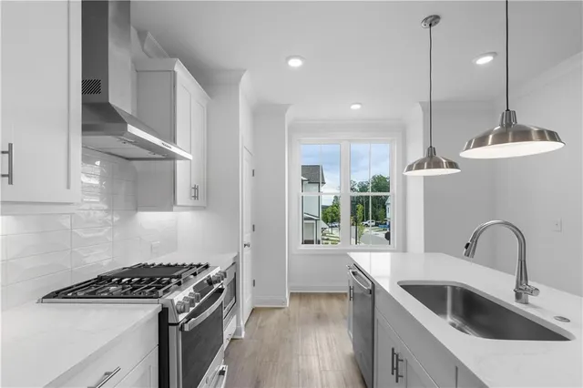 a kitchen that has a sink a stove and a wooden floor