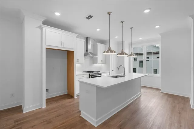 a kitchen with kitchen island a sink stainless steel appliances and wooden floor