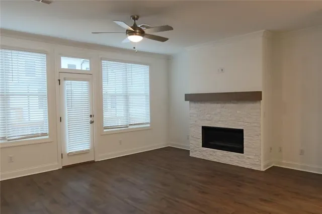 a view of an empty room with wooden floor fireplace and a window